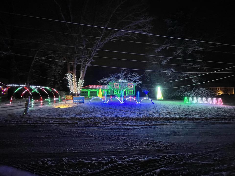 10 Jaw-Dropping Christmas Light Shows in New Hampshire You Can’t Miss in 2025 (With Insider Tips & Hidden Gems!) 4 A house decorated with colorful holiday lights, including illuminated arches and trees, stands in a snowy yard at night.