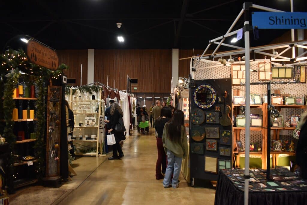 Christmas Markets Washington State 2025: Top 50 Festive Events and Holiday Fairs 5 Indoor market with people browsing various booths displaying candles, textiles, art, and crafts under bright lights.