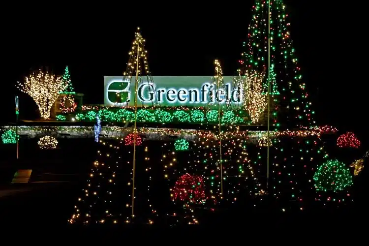 10 Dazzling Christmas Light Shows in Michigan You Can’t Miss in 2025 (Plus Free Spots & Secret Local Favorites!) 7 Greenfield sign illuminated at night, surrounded by Christmas trees and bushes decorated with red, green, and white holiday lights.