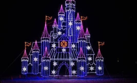 10 Dazzling Christmas Light Shows in Michigan You Can’t Miss in 2025 (Plus Free Spots & Secret Local Favorites!) 3 A castle structure outlined with colorful lights, primarily blue, purple, and pink, decorated with illuminated snowflake shapes, stands against a black night sky.