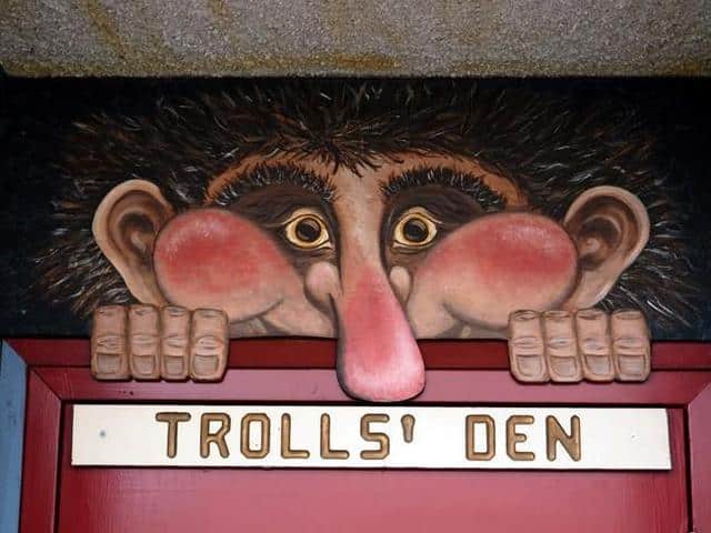 Christmas Markets Washington State 2025: Top 50 Festive Events and Holiday Fairs 1 A cartoon troll face with large eyes and a big nose peers over a red door labeled "TROLLS' DEN" in gold letters.
