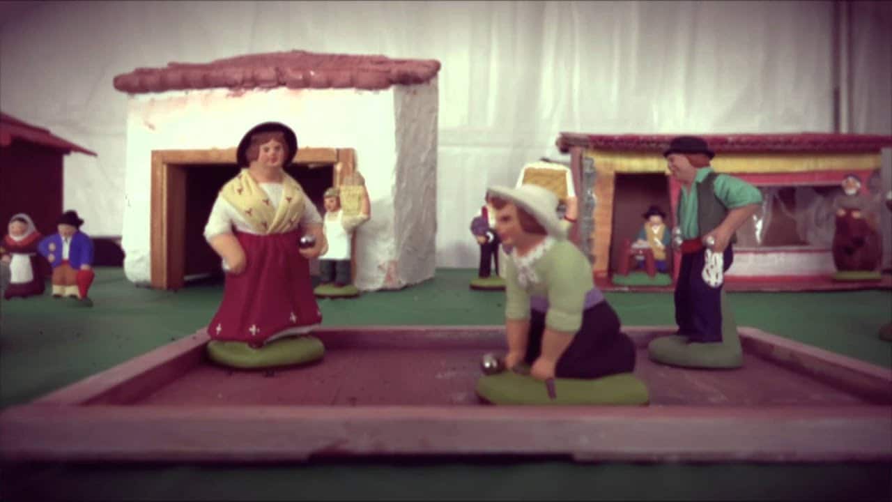 Christmas Markets Virginia 2025: Top 50 Festive Events and Shopping Destinations 1 Clay figurines depict people playing a traditional outdoor game in a miniature village setting with houses and bystanders in the background.