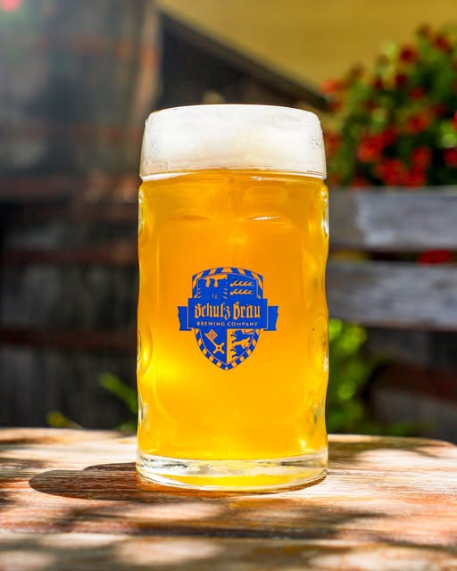 You won't Want To Miss Tennessee’s Most Magical Christmas Markets and Holiday Fairs for 2025 1 A large glass mug of pale beer with a foamy head sits on a wooden table, branded with the "Erluiz Bräu Brewing Company" logo.