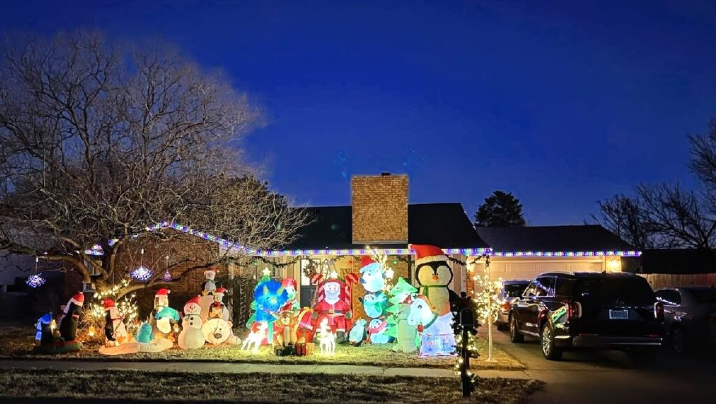 Best Christmas Light Shows New Mexico 2025: Top 7 Festive Displays Across the State 1 A house decorated with colorful Christmas lights and numerous inflatable holiday figures in the yard at dusk; a car is parked in the driveway.
