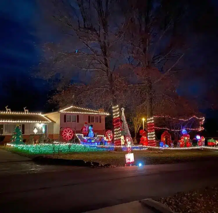 20 Magical Christmas Light Displays in Missouri You Can’t Miss This Holiday Season! (#6 is Jaw-Dropping) 2 House and yard decorated with colorful Christmas lights and illuminated holiday figures, including trees, presents, and candy canes, under large bare trees at night.