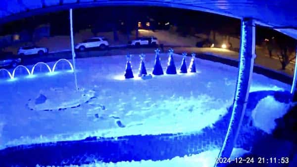 10 Dazzling Christmas Light Shows in Michigan You Can’t Miss in 2025 (Plus Free Spots & Secret Local Favorites!) 4 A snowy front yard at night is illuminated by blue and white lights, featuring five cone-shaped decorations and an archway, with cars parked on the street.
