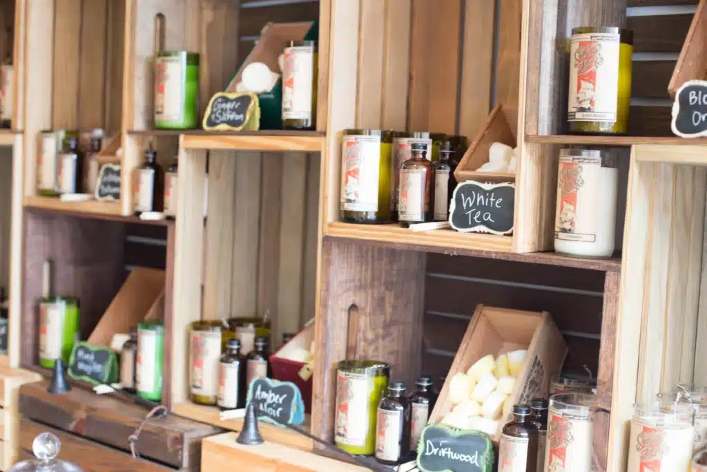 50 Magical Christmas Markets in Virginia for 2025 You Can’t Miss: Ultimate Guide to Festive Events & Holiday Shopping 1 Wooden shelves display various candles, glass jars, and soaps labeled with chalkboard signs showing scents such as "White Tea" and "Driftwood.