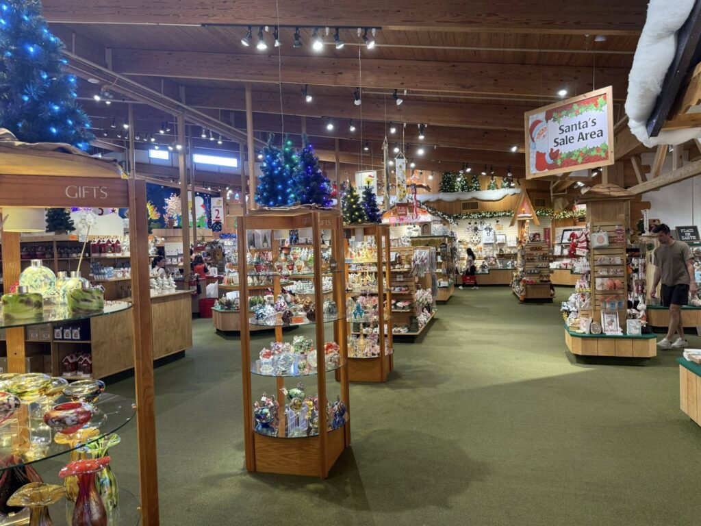 Minnesota’s 50 Best Christmas Markets to Visit in 2025 (You’ll Love #7!) 2 Interior of a gift shop with glass display cases of various items, Christmas decorations, and a sign reading "Santa's Sale Area.