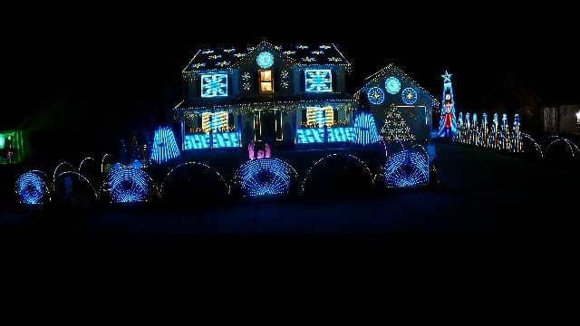 20 Magical Christmas Light Displays in Missouri You Can’t Miss This Holiday Season! (#6 is Jaw-Dropping) 1 A house decorated with blue and white Christmas lights, including light-up arches, trees, snowflakes, and holiday figures, illuminated at night.
