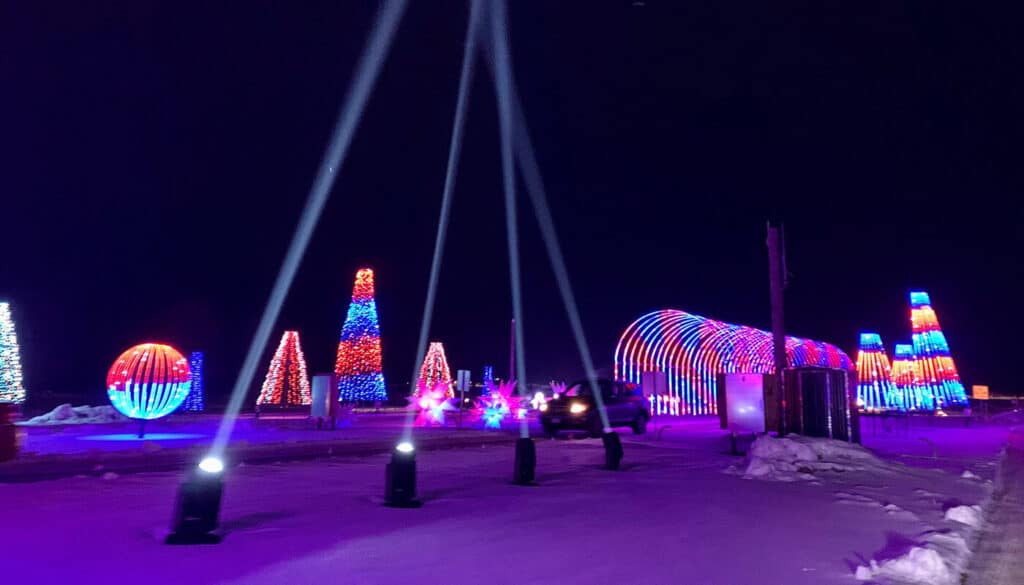20 Magical Christmas Light Displays in Missouri You Can’t Miss This Holiday Season! (#6 is Jaw-Dropping) 5 A nighttime scene of a drive-through holiday light display with colorful illuminated shapes, including trees, spheres, and a tunnel, on a snowy ground.