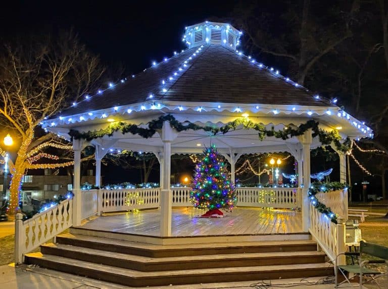 Minnesota’s 50 Best Christmas Markets to Visit in 2025 (You’ll Love #7!) 6 A gazebo decorated with string lights and garland, featuring a lit Christmas tree inside, is pictured at night in a park.