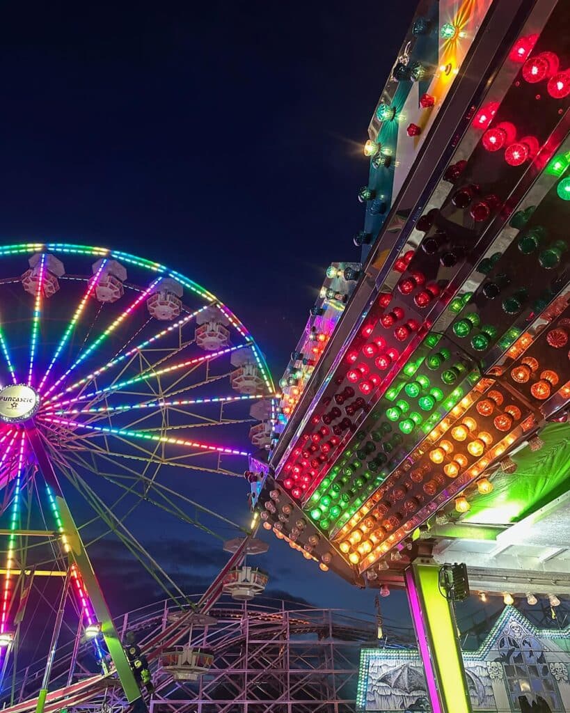 Christmas Markets Washington State 2025: Top 50 Festive Events and Holiday Fairs 3 A brightly lit Ferris wheel and amusement ride at night, with colorful lights illuminating the scene against a dark sky.
