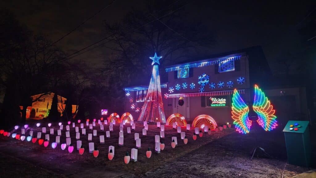 7 Jaw-Dropping Christmas Light Displays in New Jersey That Will Blow Your Mind (And Melt Your Frosty Heart!) 3 A house decorated with colorful Christmas lights, including a large tree, snowflakes, candy canes, and wings, all illuminated at night.