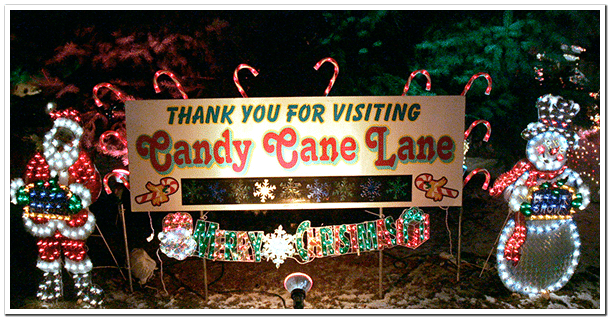 18 Magical Christmas Light Displays in Wisconsin You Can’t Miss in 2025 (Drive-Thrus, Walk-Thrus & Secret Neighborhood Gems!) 3 Sign reading "Thank you for visiting Candy Cane Lane" surrounded by Christmas lights, candy cane decorations, a Santa figure, a snowman, and holiday greenery.
