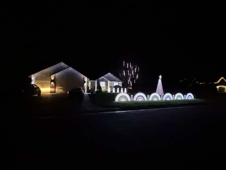 Kansas Christmas Light Shows 2025: The Ultimate Guide to the Most Stunning Holiday Displays You Can’t Miss! 7 A house decorated with white roof lights, illuminated arches, and a lit-up tree-shaped display in the yard at night.
