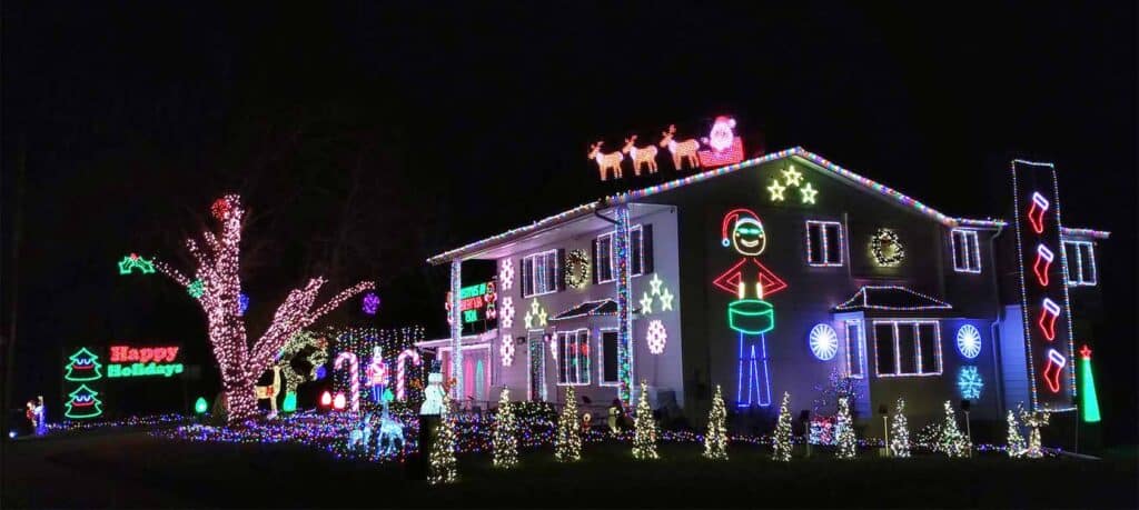 Minnesota’s Top 5 Unmissable Christmas Light Shows for 2025—Discover Hidden Gems and Festive Magic Near You! 3 A house decorated with colorful Christmas lights and neon holiday figures, including Santa, reindeer, snowflakes, and candy canes, with "Happy Holidays" displayed on the lawn.