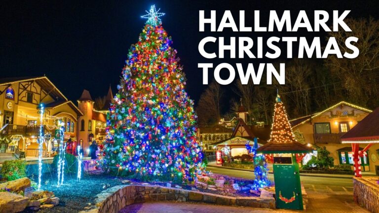 A large, decorated Christmas tree with colorful lights stands in the center of a festive town square at night, surrounded by lit buildings and holiday decorations. "HALLMARK CHRISTMAS TOWN" text is overlaid.
