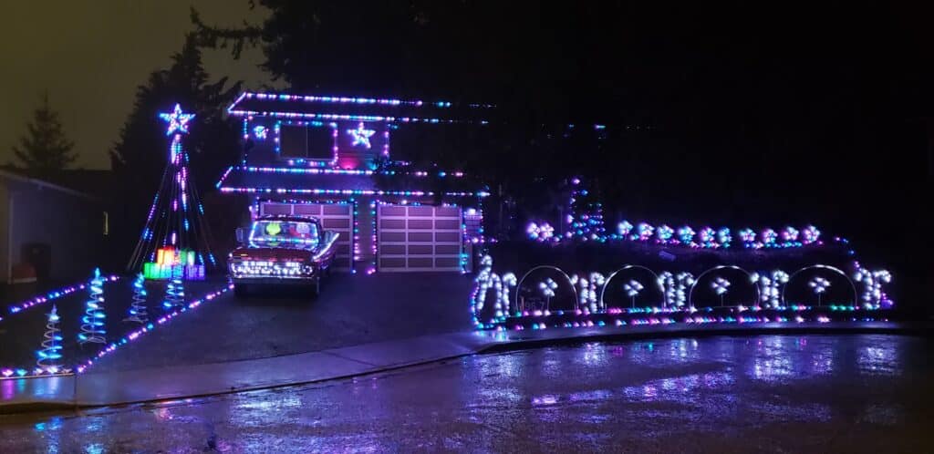 11 Jaw-Dropping Christmas Light Displays in Washington for 2025—You Won’t Believe #7! 2 A house and yard decorated with colorful Christmas lights at night, including lights on the car, trees, and arches along the driveway.