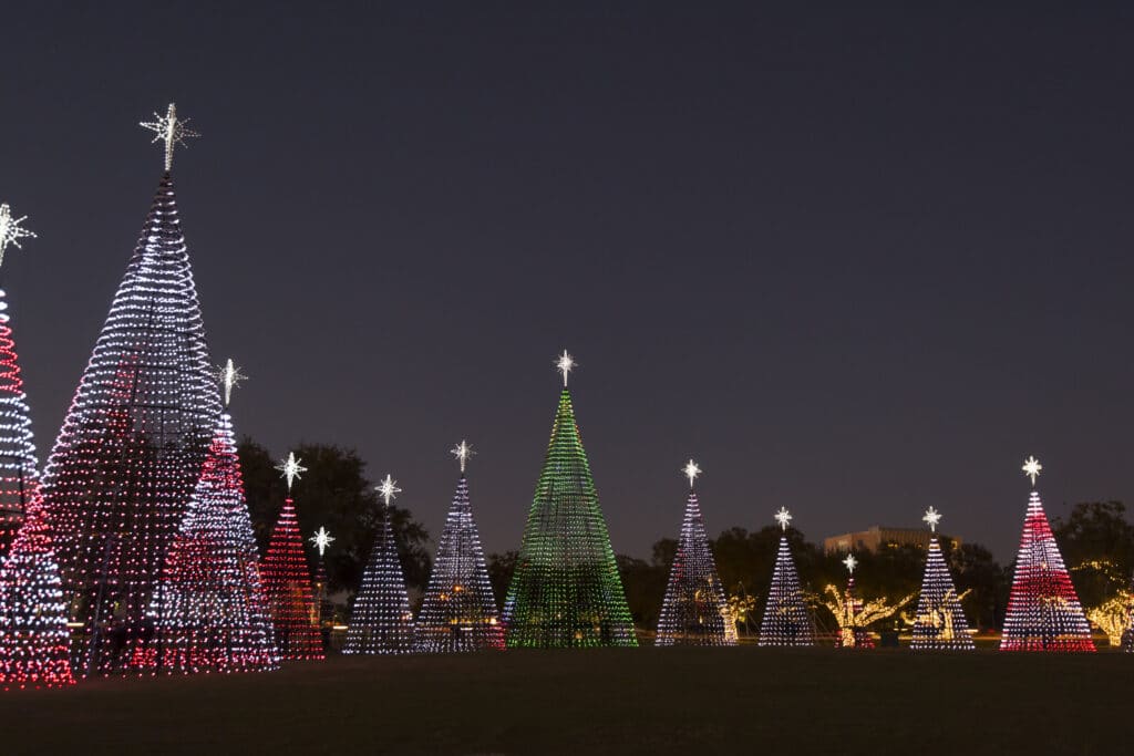 Louisiana’s Ultimate 2025 Christmas Light Displays: Discover The Most Magical, Must-See Holiday Shows You Can’t Miss! 9 Several large cone-shaped structures decorated with red, white, and green holiday lights are displayed outdoors at night, resembling Christmas trees.