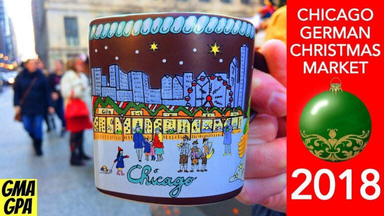 A hand holds a festive mug with a Chicago cityscape at the Chicago German Christmas Market, 2018, with people and holiday decorations in the background.