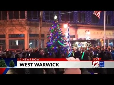 Christmas Markets Rhode Island 2025 Best Festive Events and Vendor Locations 1 A crowd gathers around a decorated and lit Christmas tree in downtown West Warwick during a live news broadcast.