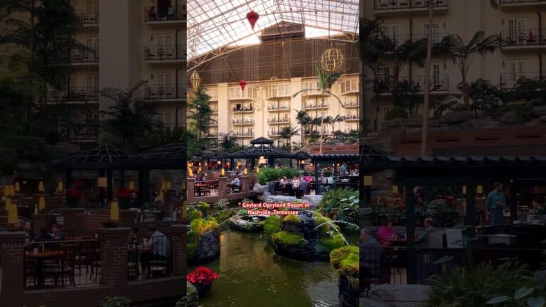 Indoor garden with a pond, tropical plants, seating areas, and people dining under a glass atrium at Gaylord Opryland Resort in Nashville, Tennessee.